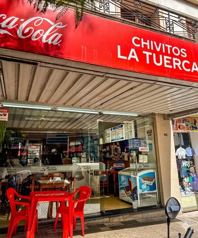 Fachada de Chivitos La Tuerca con su cartel rojo y mesas en la vereda