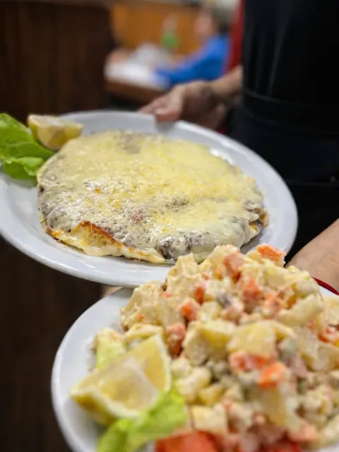Moza sirviendo una milanesa con muzzarella gratinada y ensalada rusa