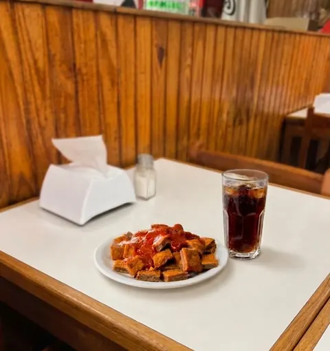 Milanesa picada con salsa y un refresco en una mesa del salón